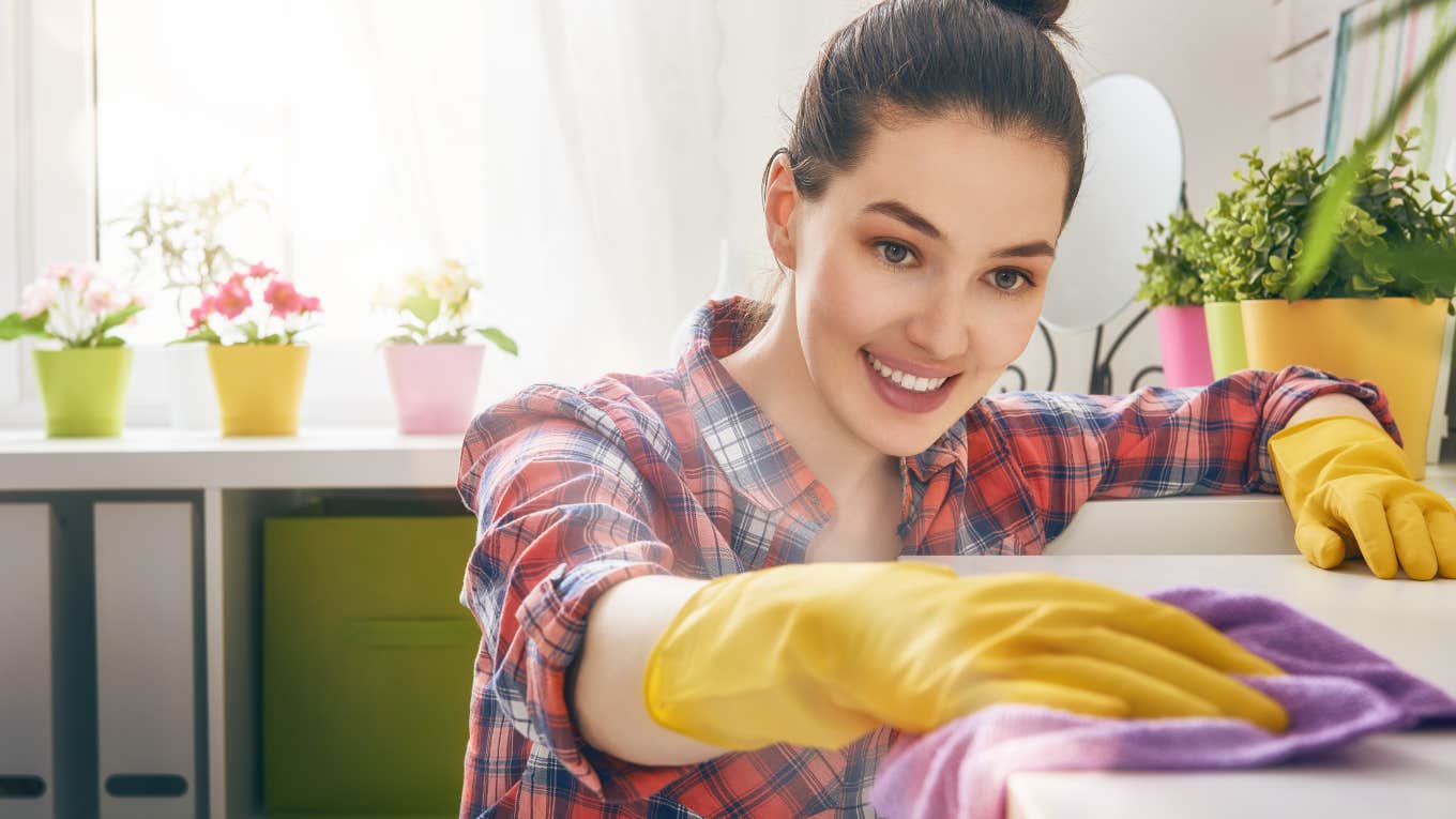 woman cleaning countertop with cloth and rubber gloves
