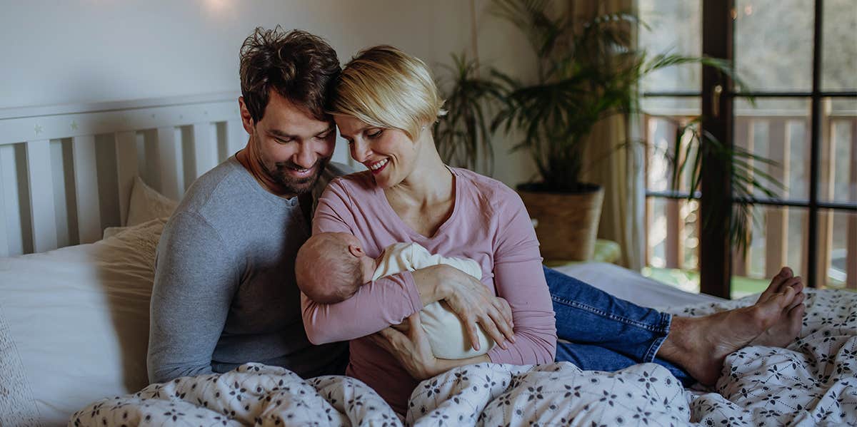 parents holding newborn baby in bed