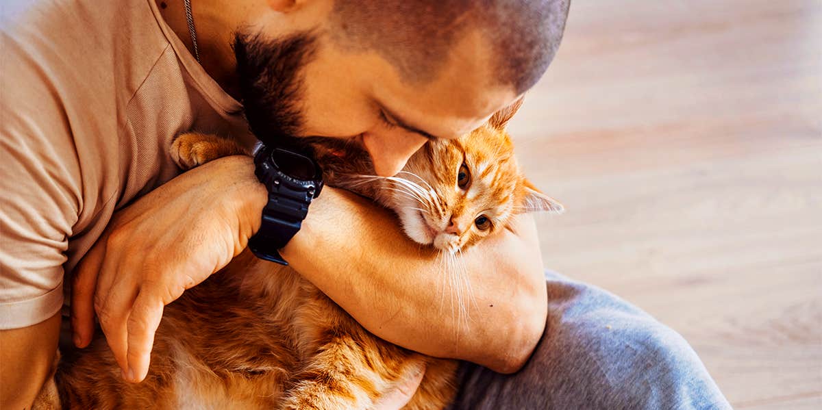 man cuddling with cat