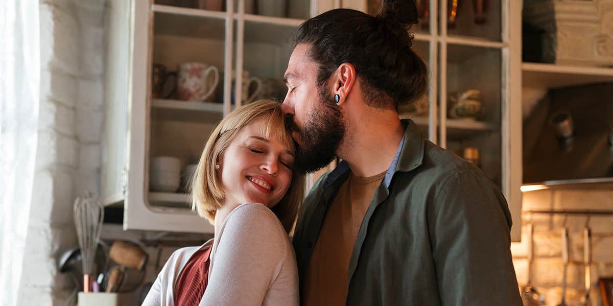 man kissing woman's head