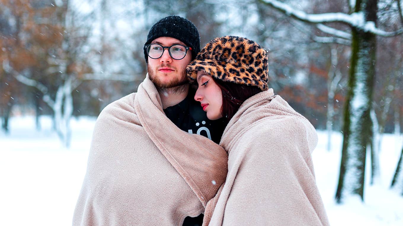 couple cuddling under blanket in the snow