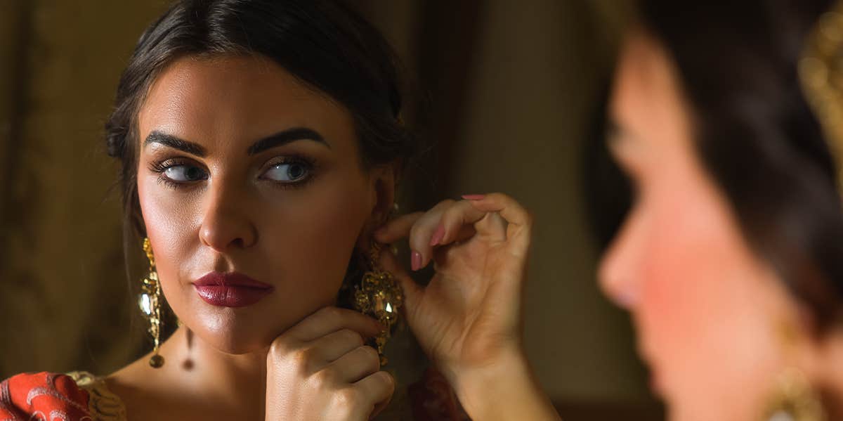 Ways To Flirt Like A Romantic Queen Of Ye Olden Times woman putting on earrings
