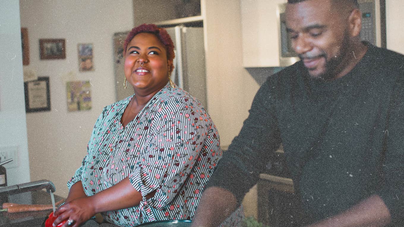 Woman staring knowingly at man while they wash dishes 