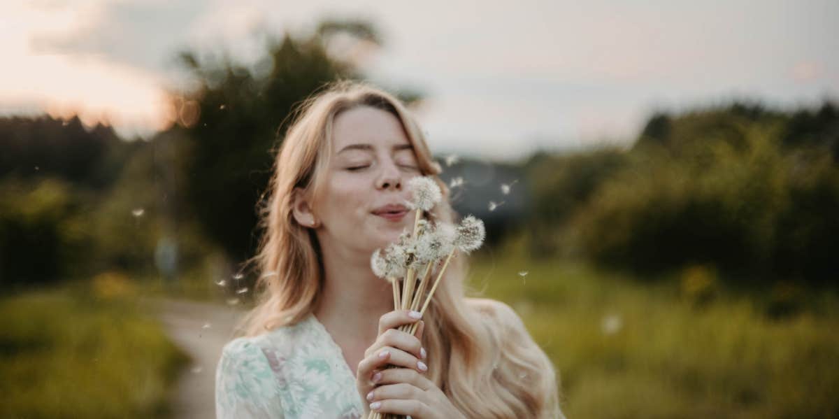 woman blowing a dandelion