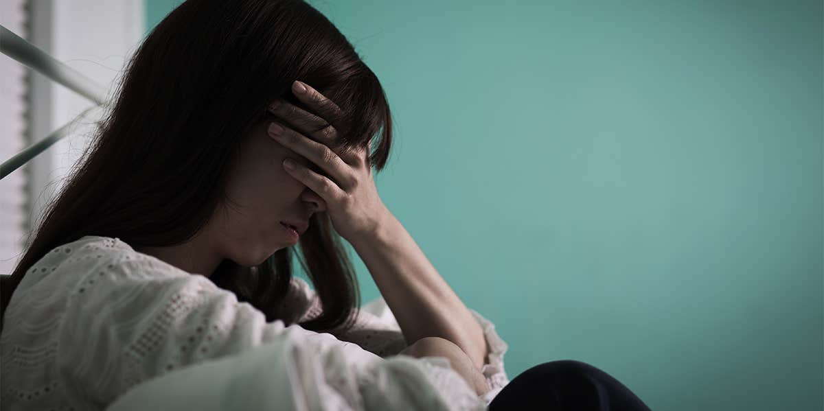 How To Know If You Have A 'Father Wound' — And If It Still Affects You Today sad woman covering face