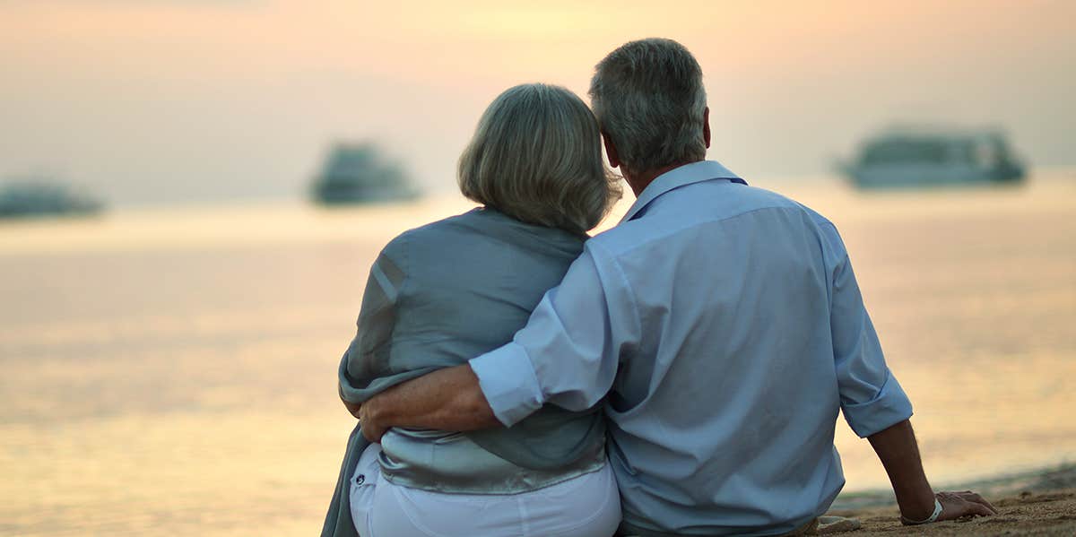 older couple watching sunset by water