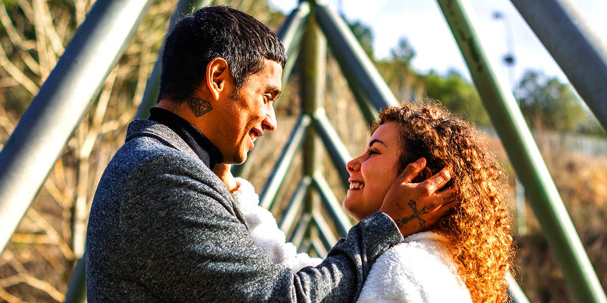 man holding woman close on bridge