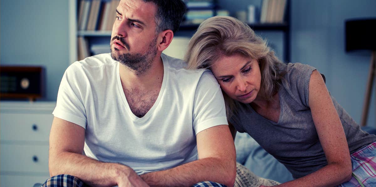 unhappy couple sitting on bed in pajamas upset about their sexless marriage