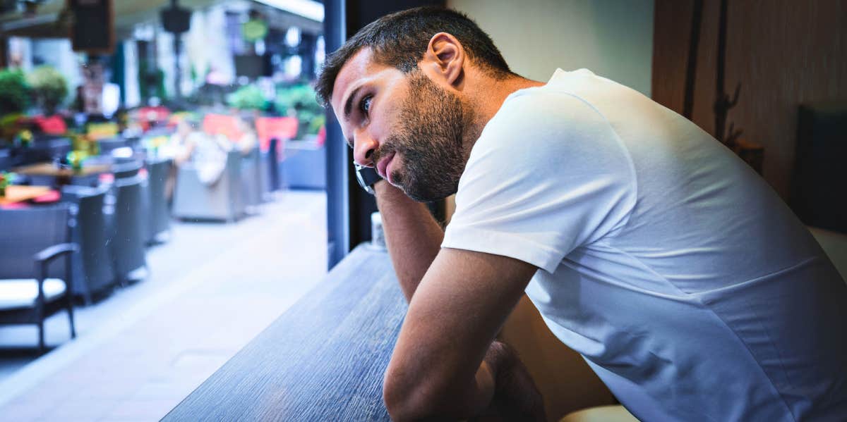 man looking out of a window regretting breaking up