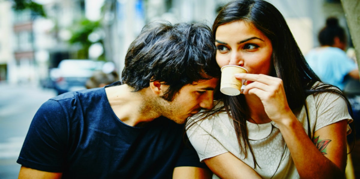 woman sipping from cup with man resting head on her shoulder