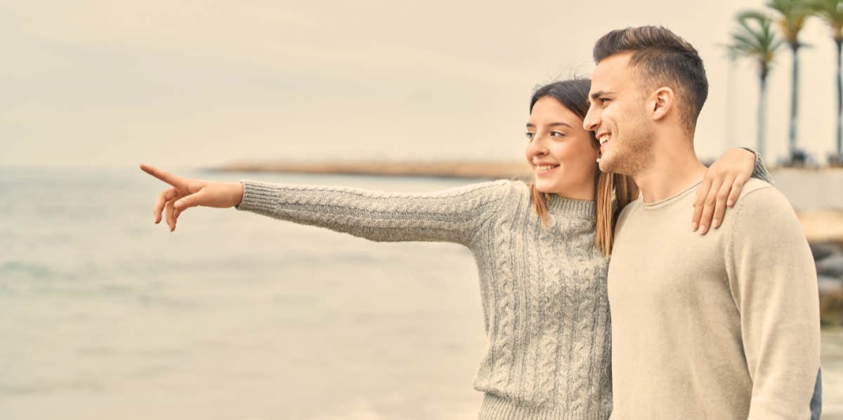 couple pointing at ocean