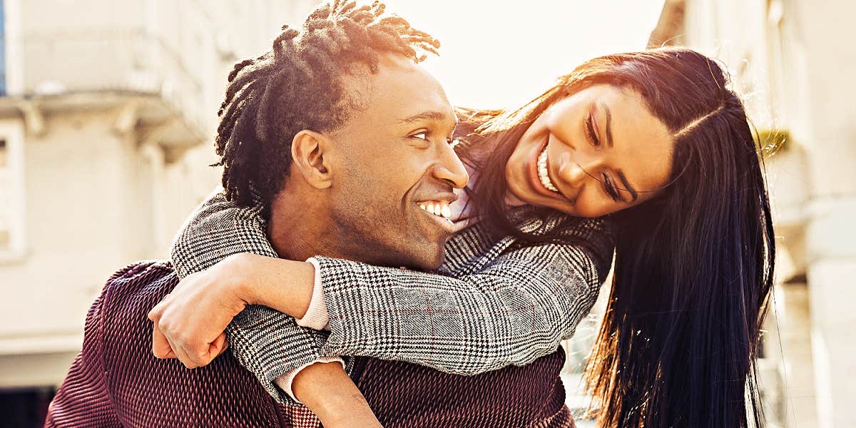 man and woman smiling at one another, her on his back