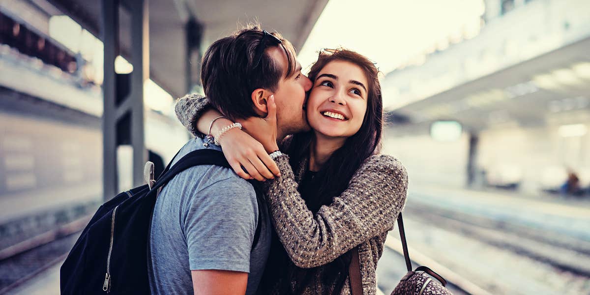 Things guys can do to keep love flowing man kissing a woman on a train platform while she laughs