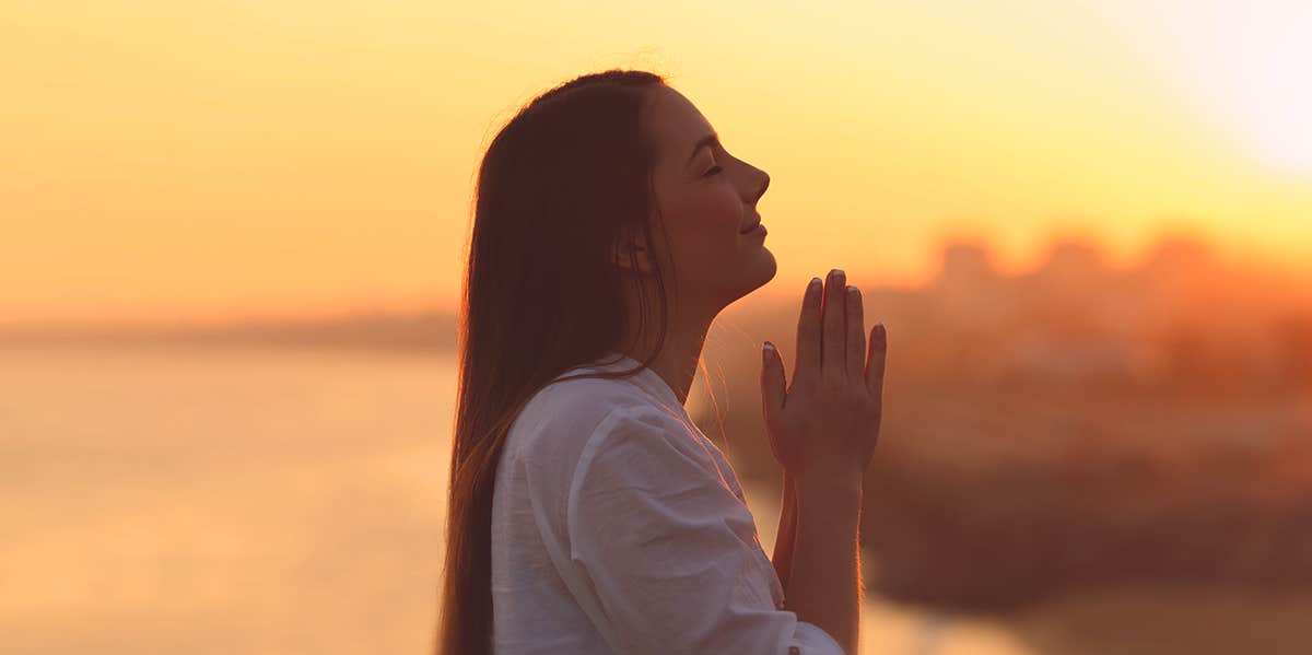 woman praying during sunset