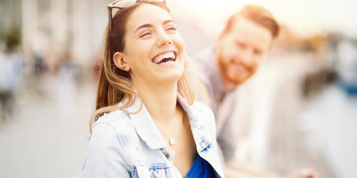 confident woman laughing, man in the background