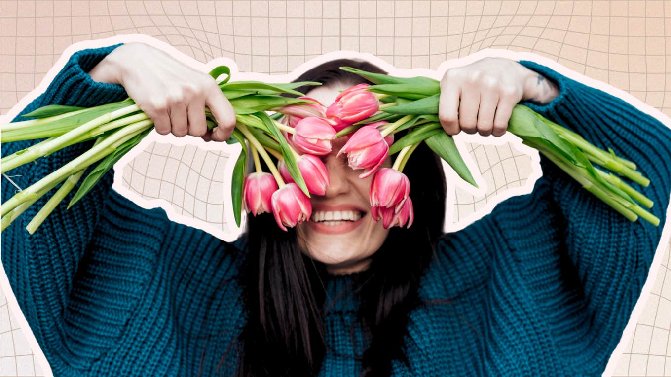 Woman smiling holding flowers over her eyes 