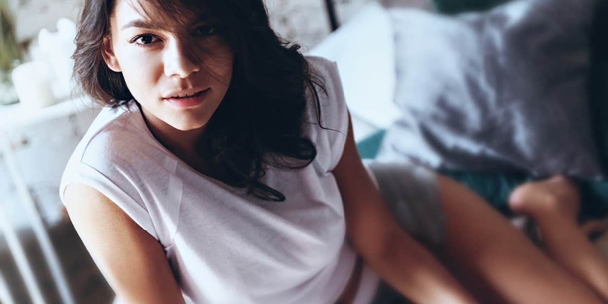 woman sitting on a bed, looking shady