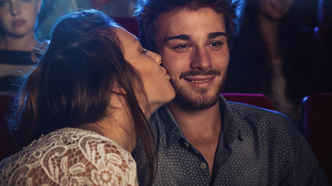 Romantic loving couple at the cinema, a girl is kissing her boyfriend on his cheek