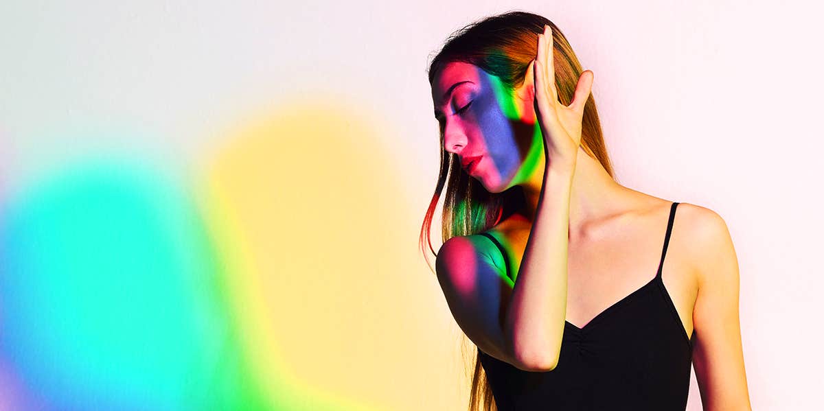 woman holding hand up with rainbow reflection