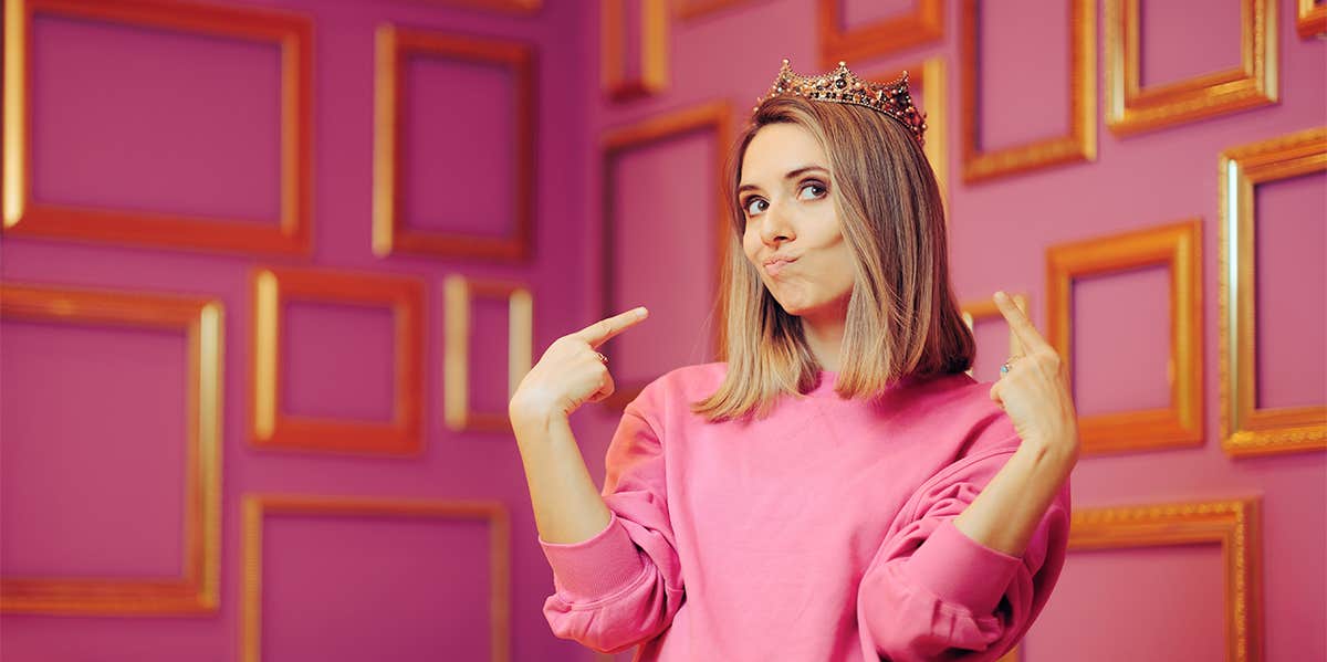 Woman wearing a crown pointing at herself 