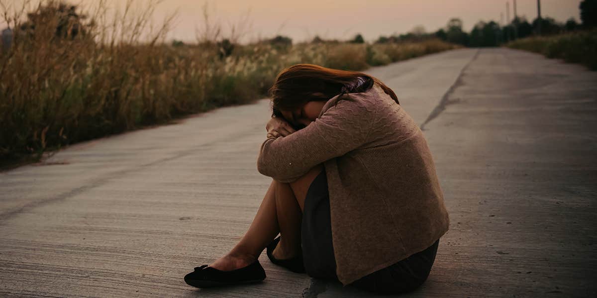 upset girl sitting alone outside curled up