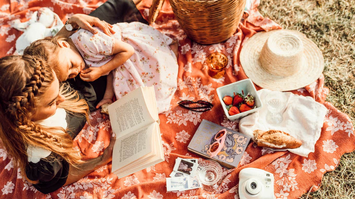 Mother loving on her daughter and self, picnic and reading 