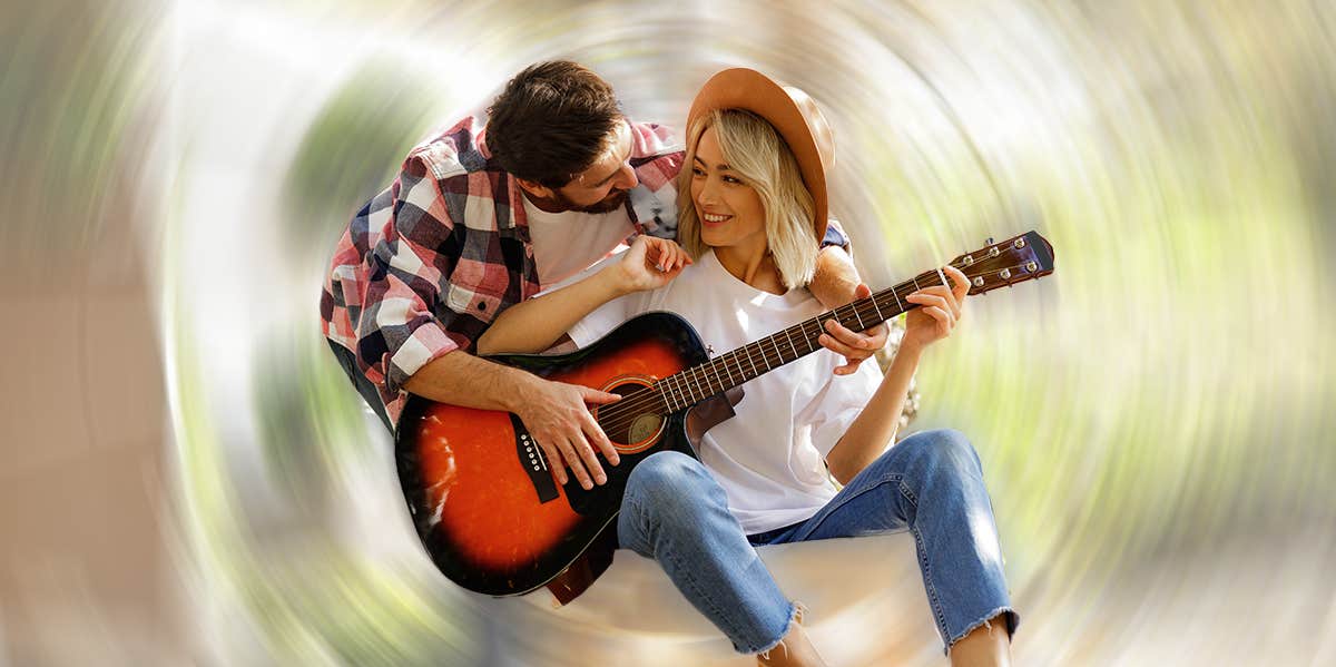 man showing woman how to play guitar