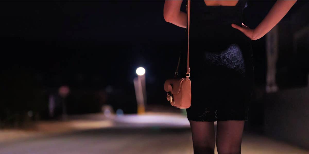 woman in black dress walking down road at night