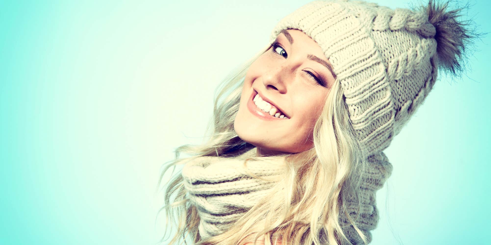 pretty blond woman wearing a beanie smiling and winking