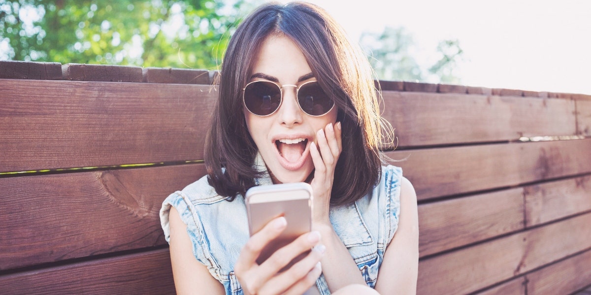 woman looking surprised at her phone