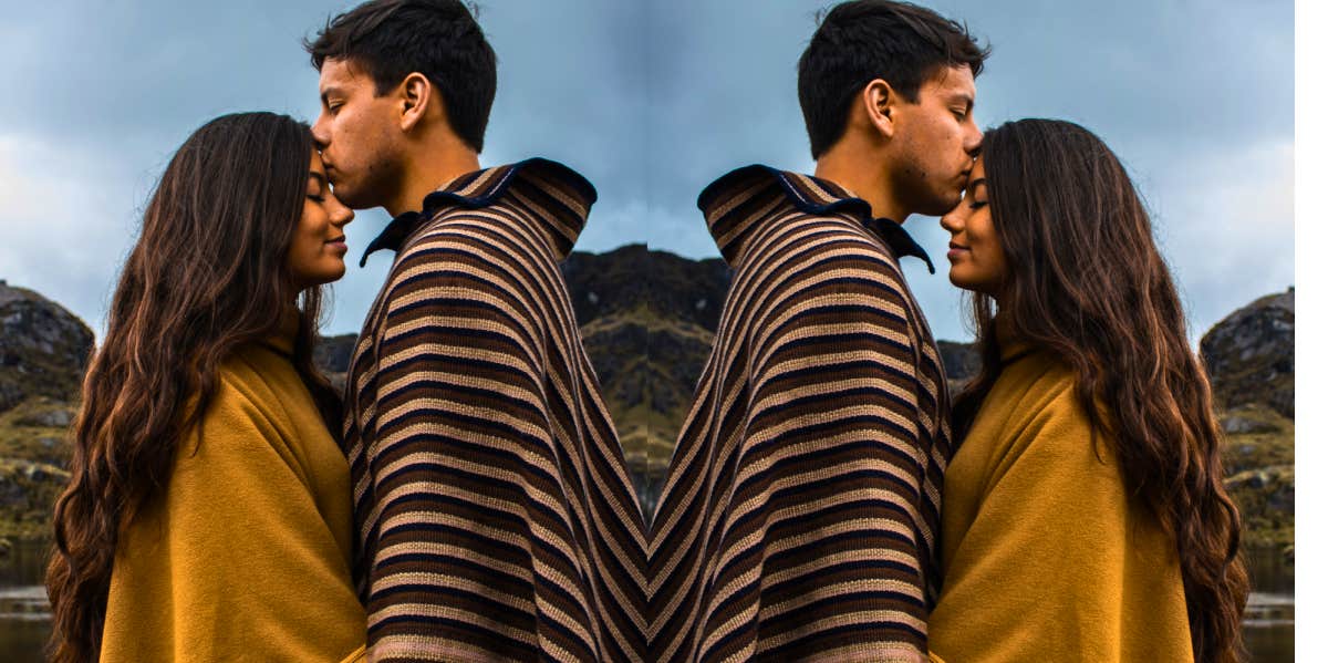 empathetic couple standing together with the man kissing the woman's head