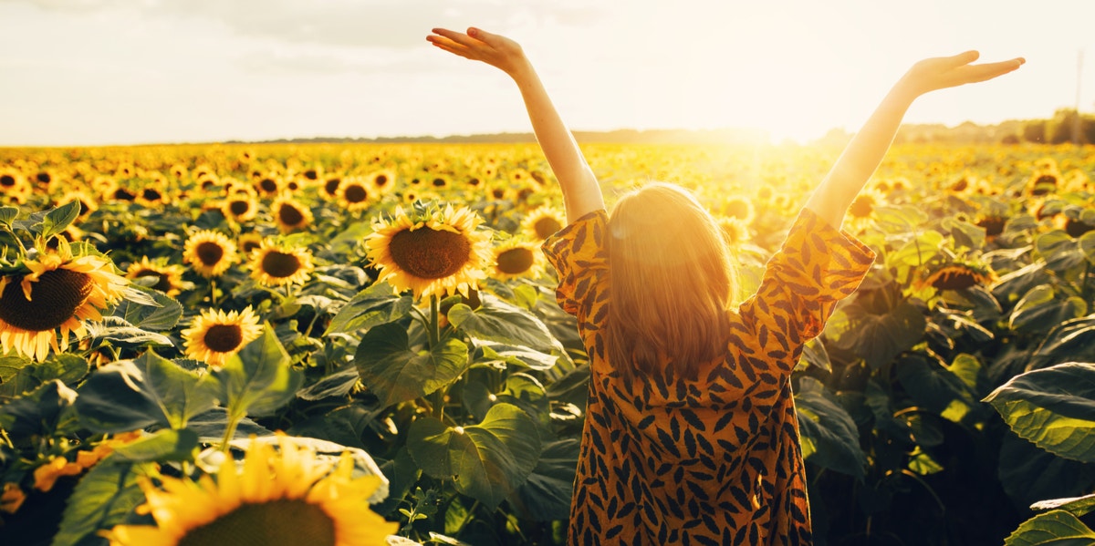 4 Research-Backed Strategies That Will Help You Feel Instantly Happier woman in sunflower field