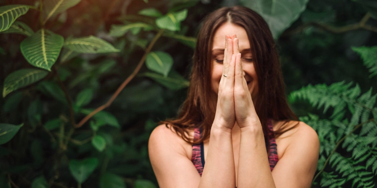 woman meditating with green behind her