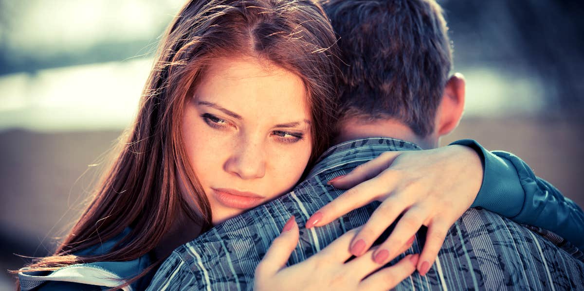 woman looking over toxic boyfriend's shoulder wondering how to break up with him