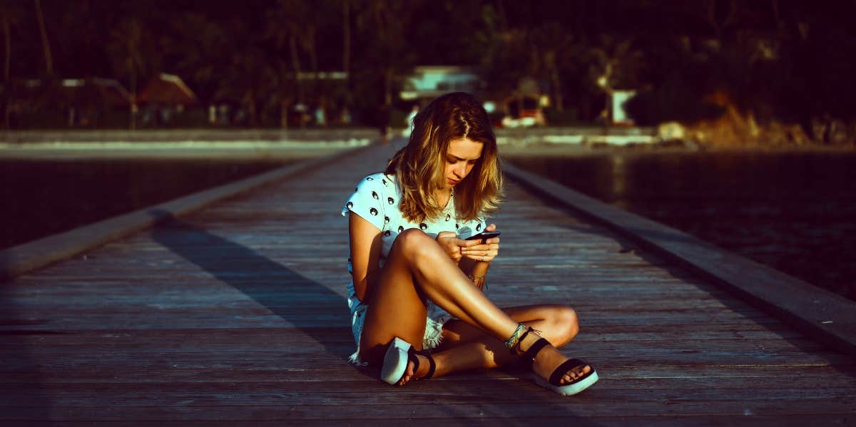 girl sitting on the ground breaking up with someone over text