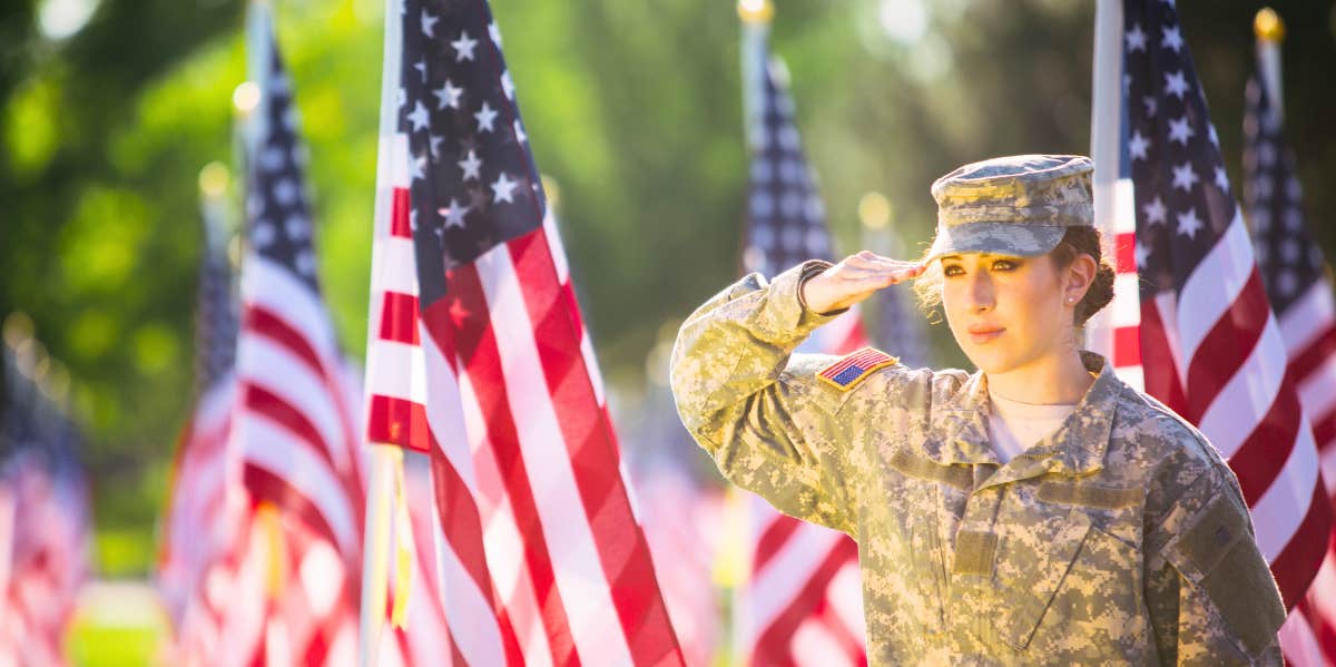 Hispanic American Female Soldier in uniform saluting in front of American flags