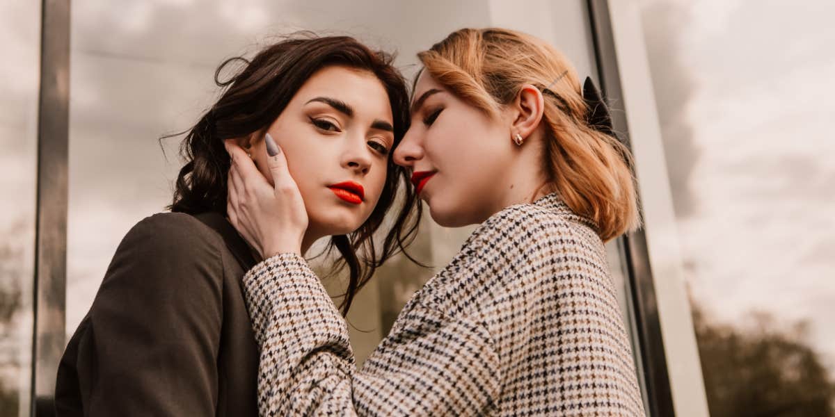 two women embracing, a brunette looking at the camera