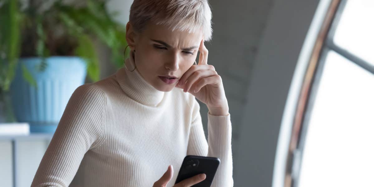 woman looking at phone upset