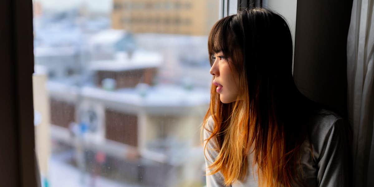 sad woman sitting near window