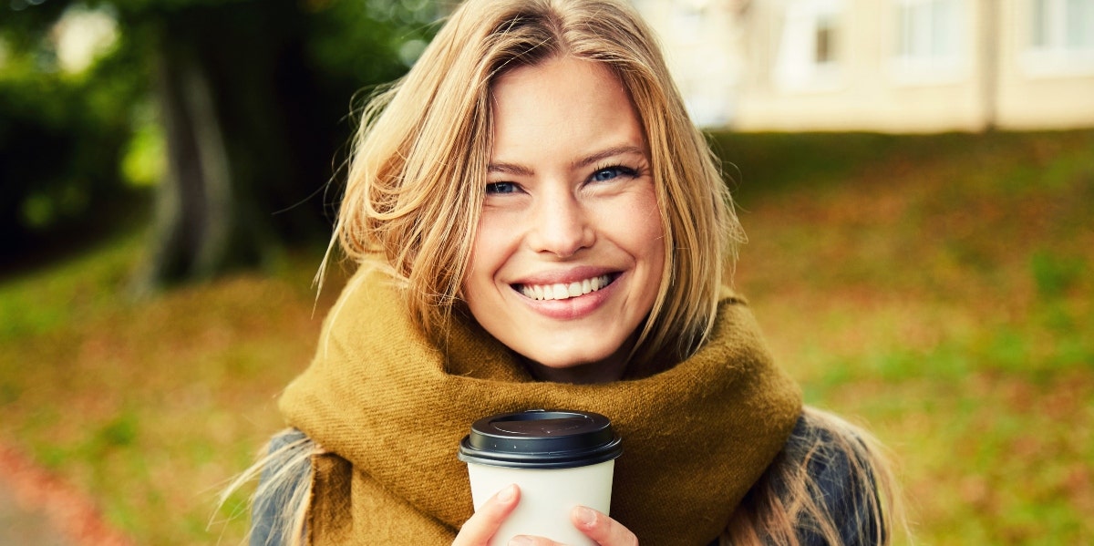 smiling woman in scarf drinking coffee