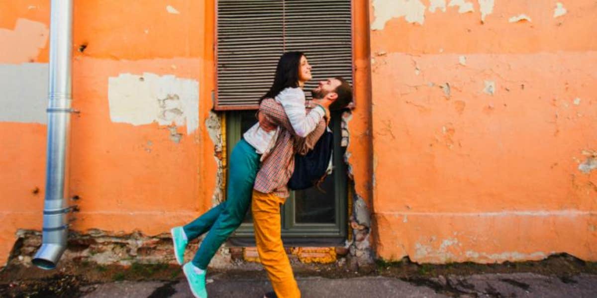 man embracing woman tightly and sweeping her off her fight