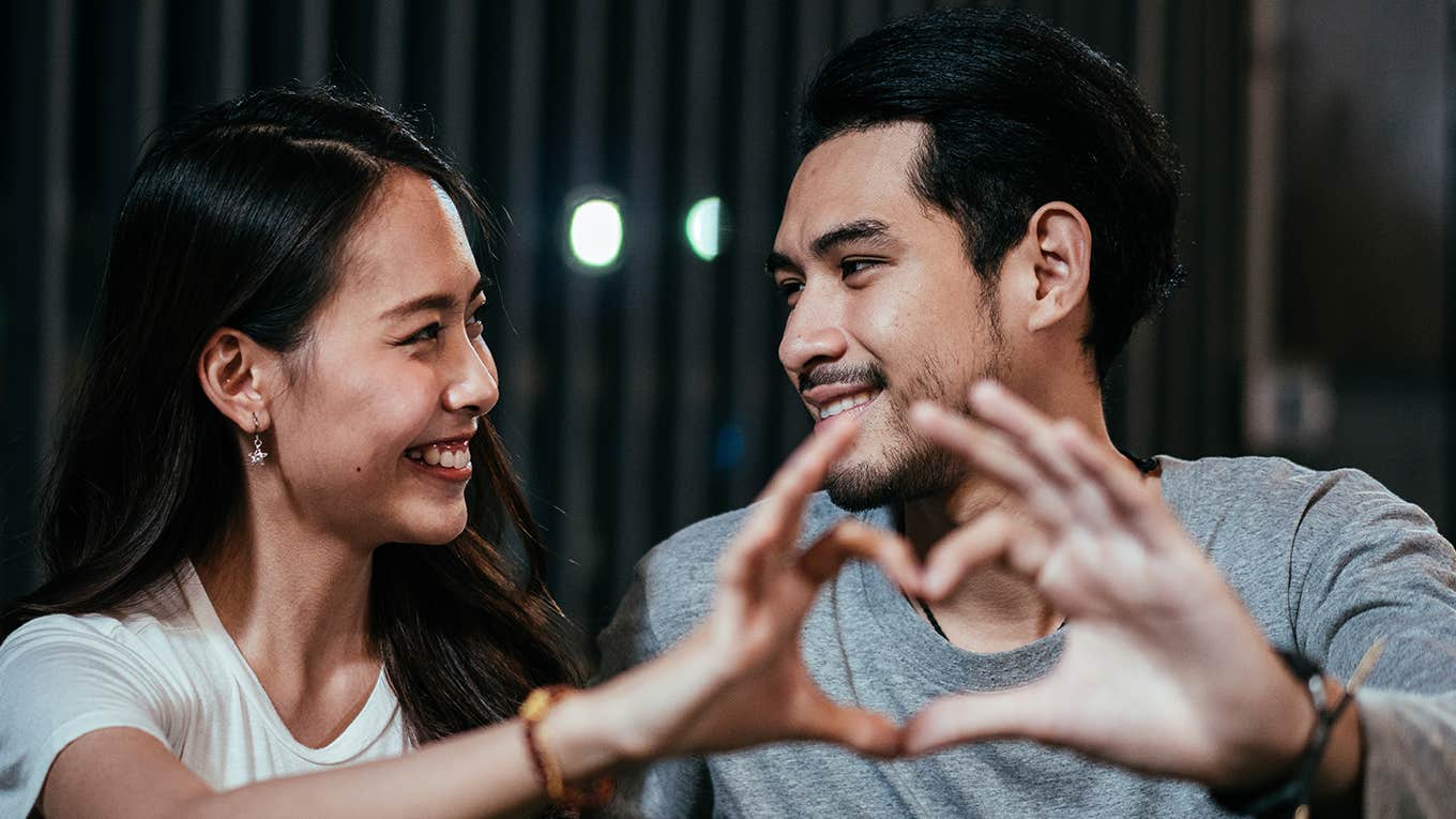 man and woman making heart shape with their hands