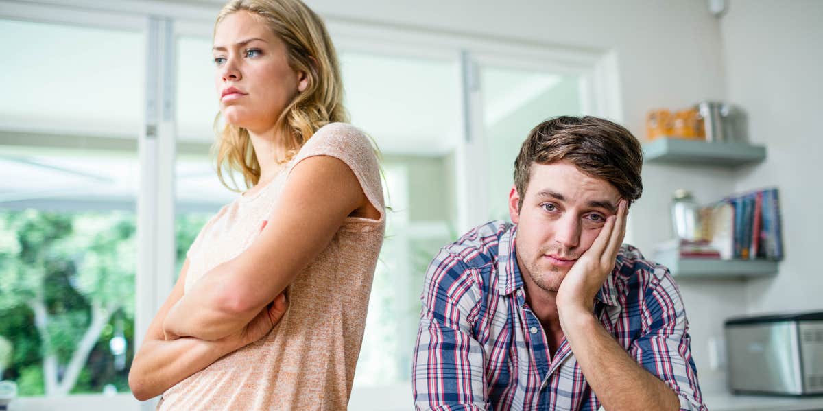 How To Fix A Sexless Marriage: 10 Expert Tips annoyed woman in the kitchen with her back to husband looking resigned