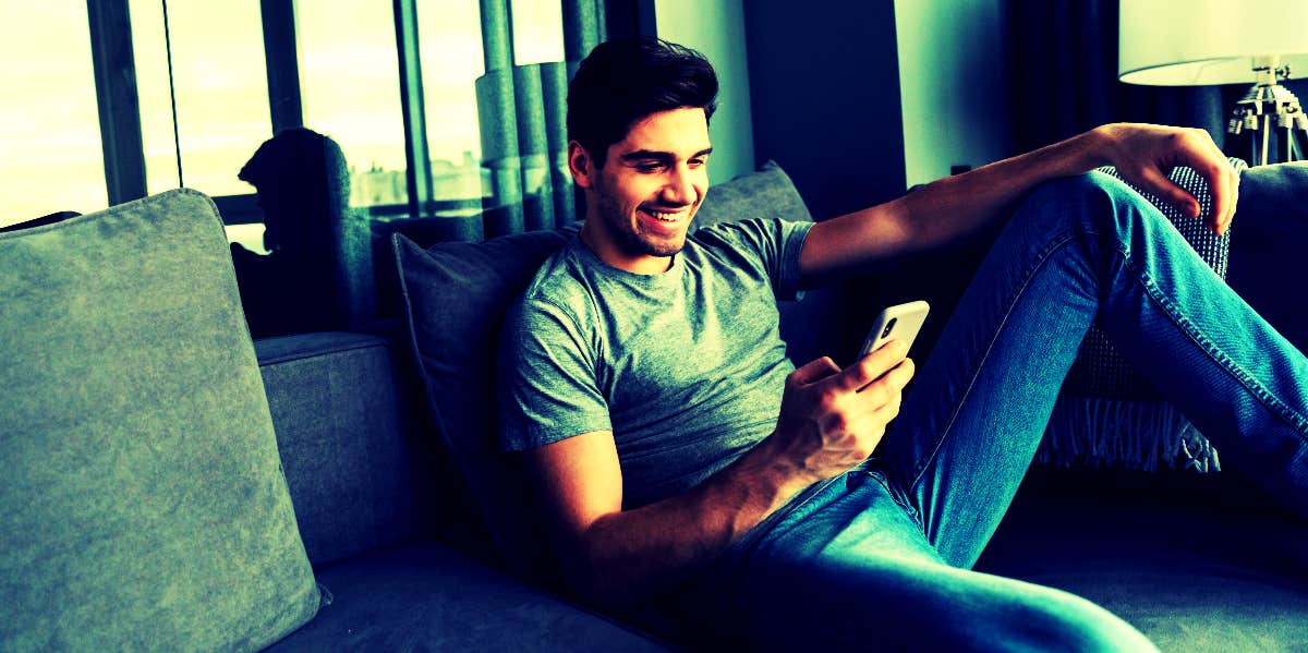 guy sitting on couch reading flirty text messages