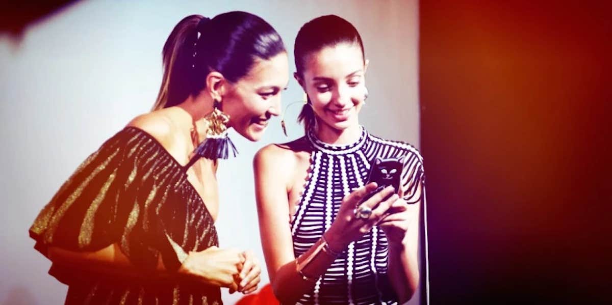 How To Get A Guy To Ask You Out Over Text two women smiling while excitedly looking at the screen of the phone one of the women is holding