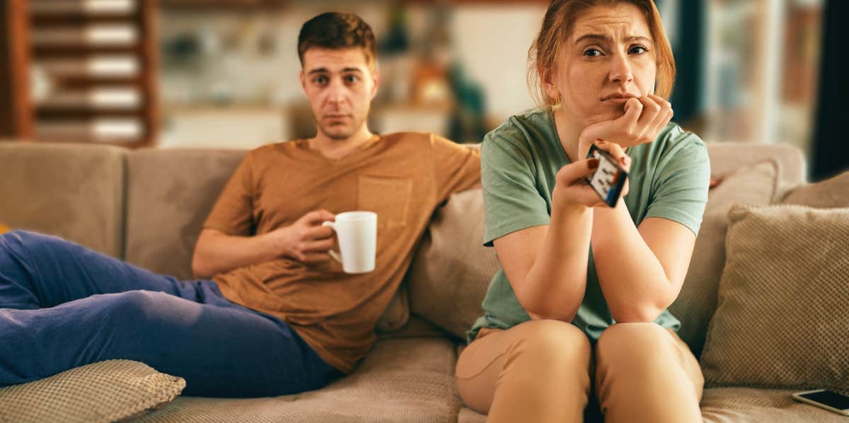 couple sitting on couch bored looking at TV
