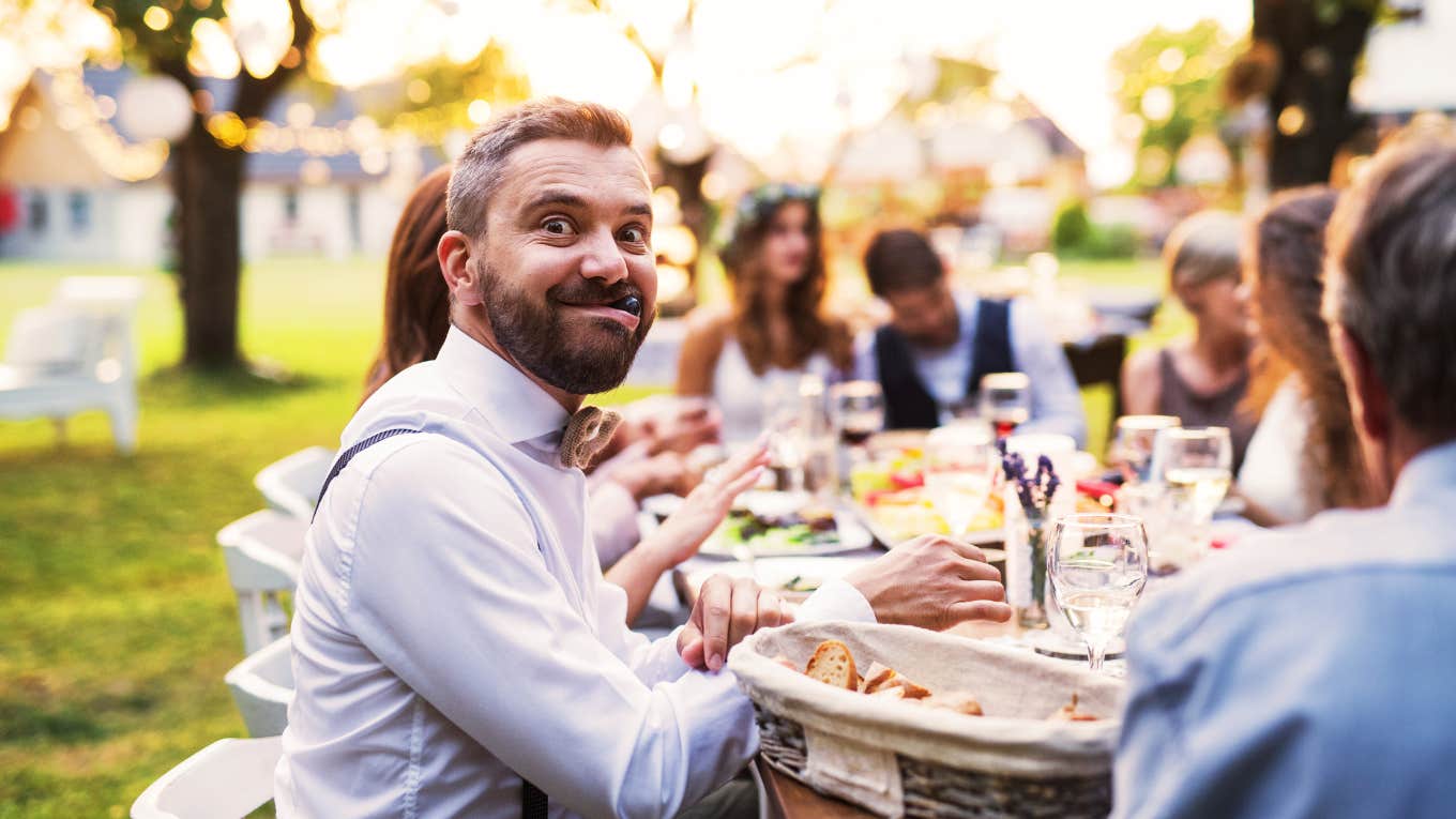 man is a guest at a wedding making a silly face