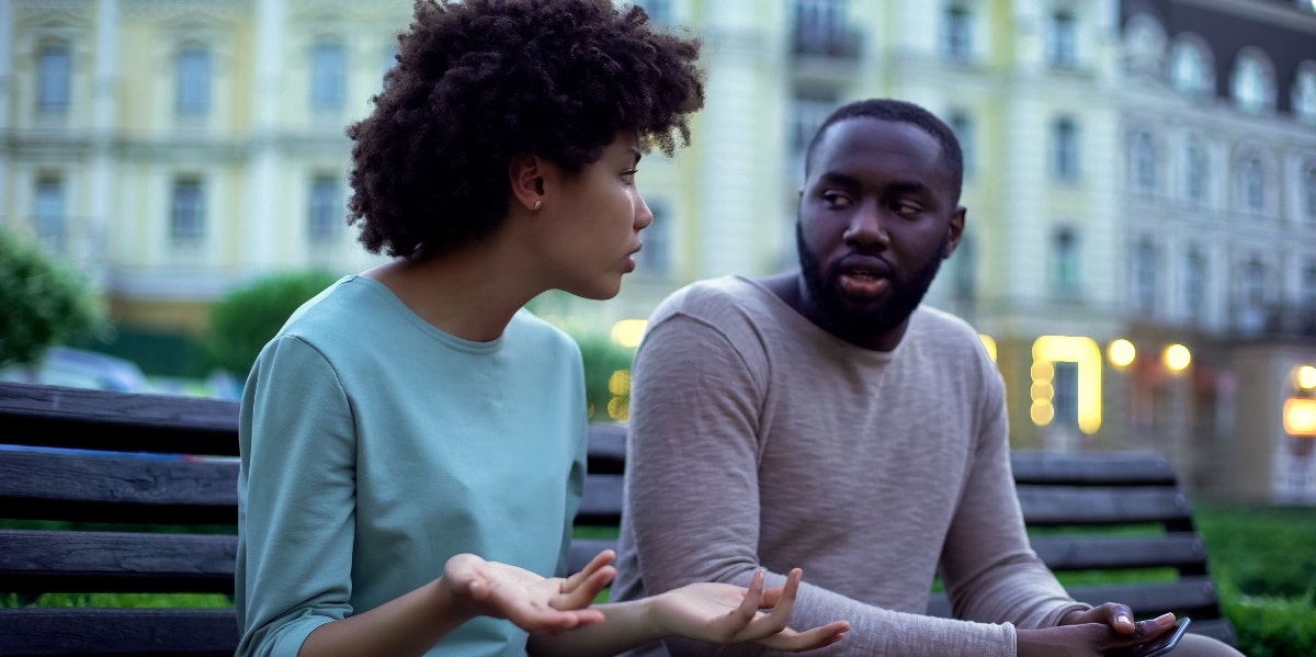 man and woman talking on park bench