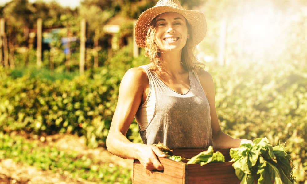 Smiling woman with produce harvest from garden