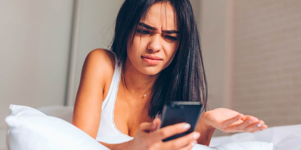 How To Know If Someone's Blocked You In Texts Or On Social Media young woman looking at her phone wondering if someone blocked her